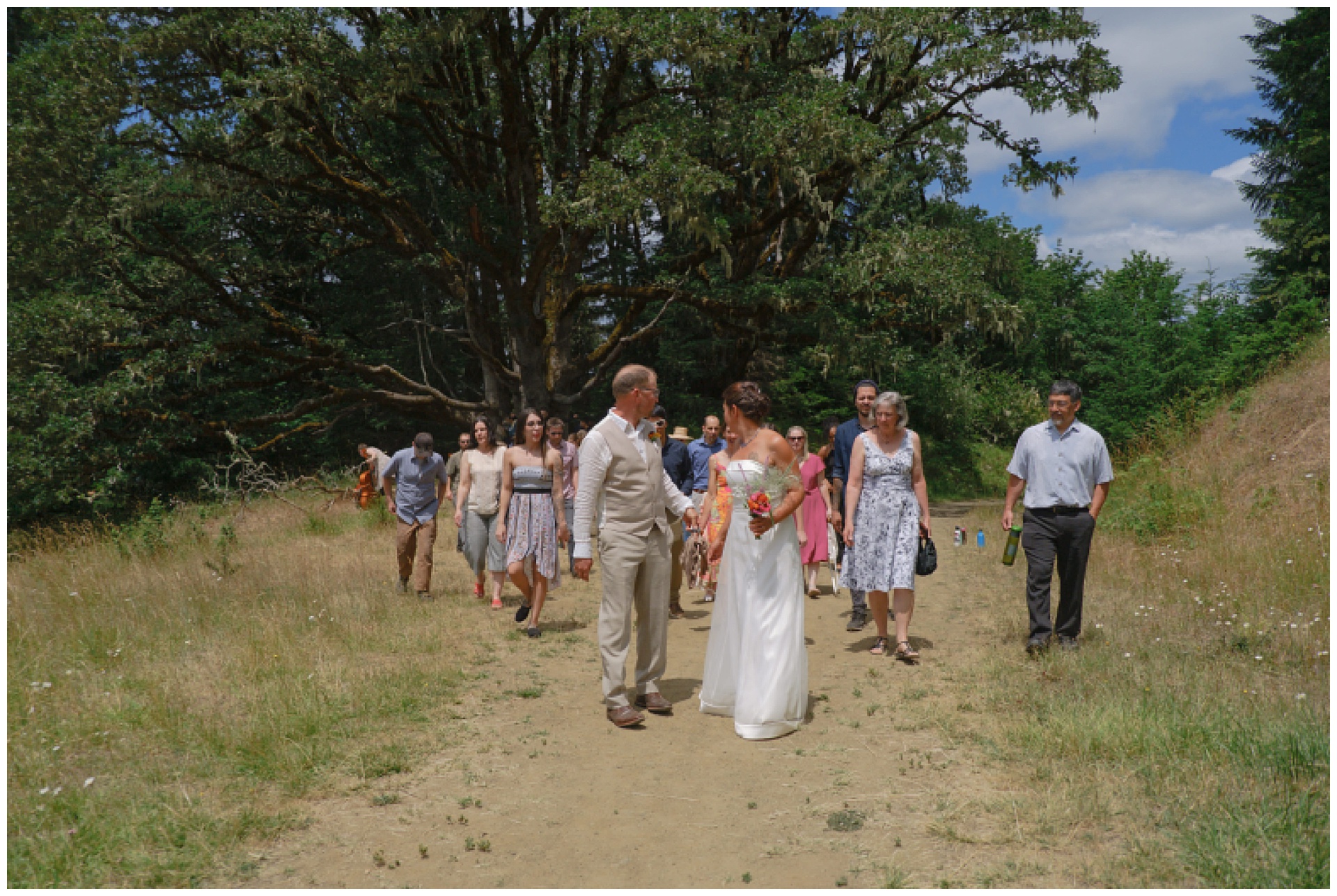 Bride and groom lead their guests along a mountain path.